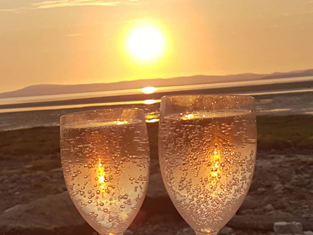 a sunset with champagne glasses in the foreground