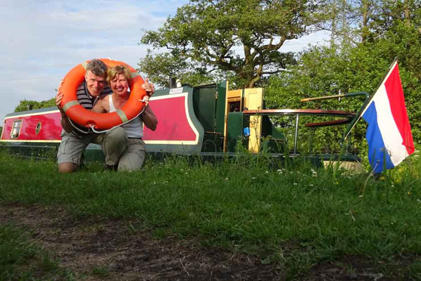 a couple pose together with a life ring around both of their necks, in the background is rose the narrowboat and trees carrying spring foliage